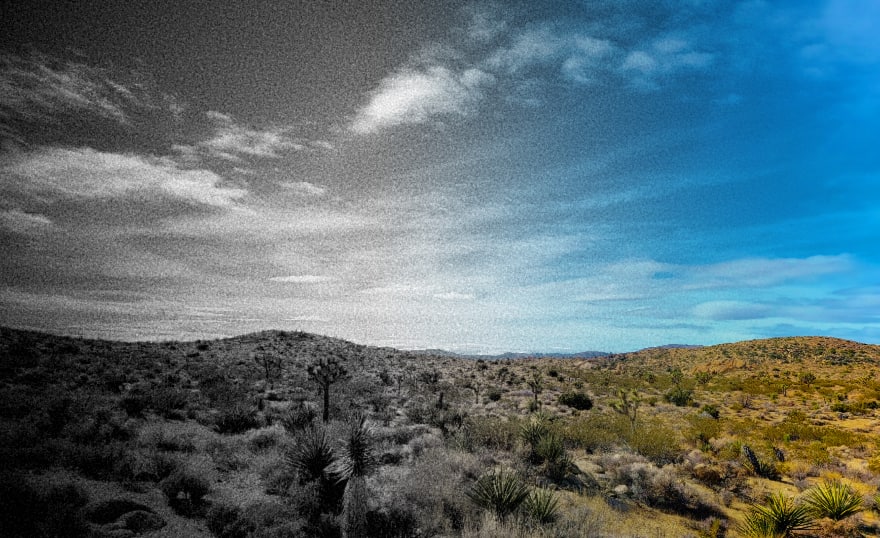 Desert vista with a gradient effects going from black-and-white and grainy on the left to highly saturated colours on the right, including a bright blue sky.